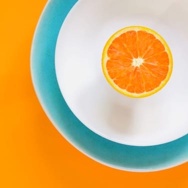 image of half an orange on a plate with an orange background